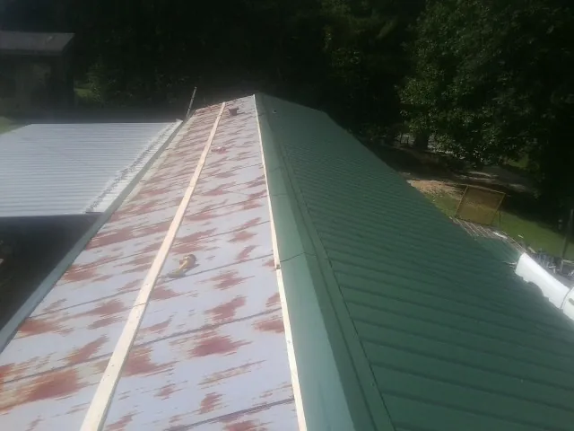 Old rusted panels beside newly installed green metal roofing — Wind Damage Roof Repair by Roofing Brothers in Richwood