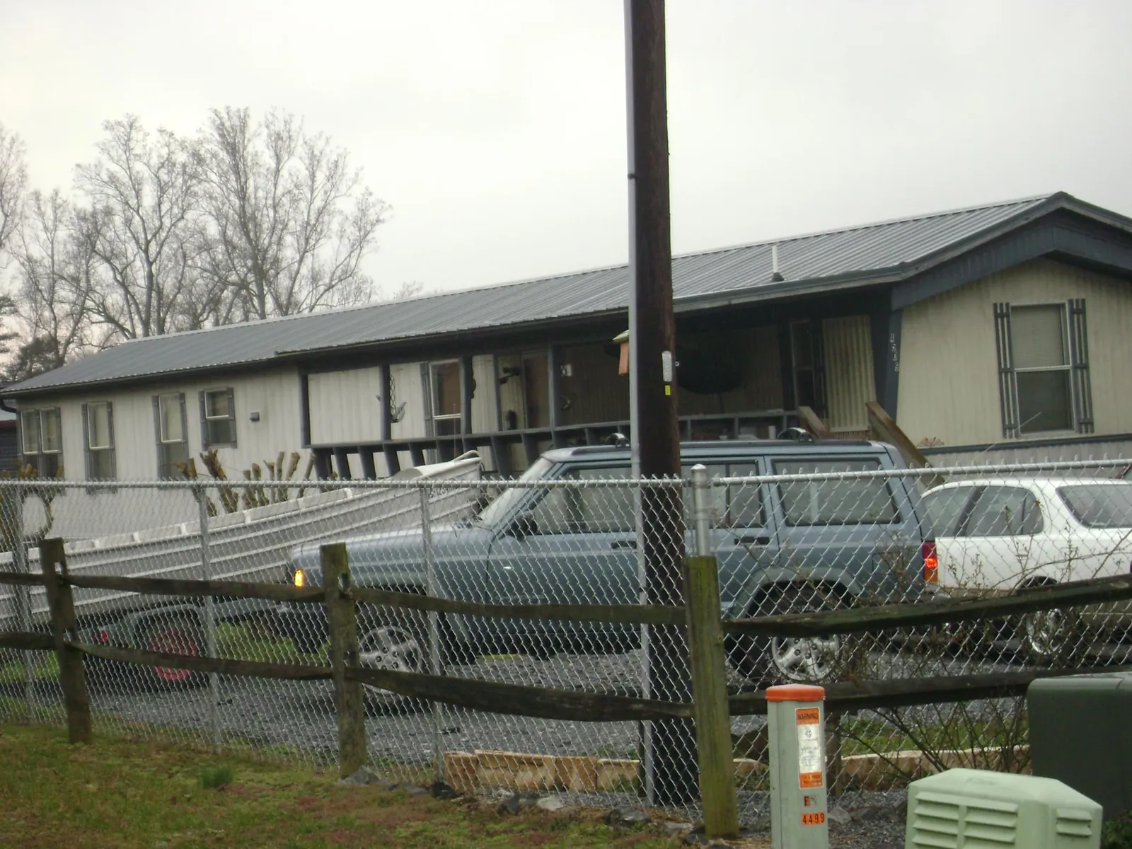 Dark metal roof on a long single story building behind a chain link fence in Richwood