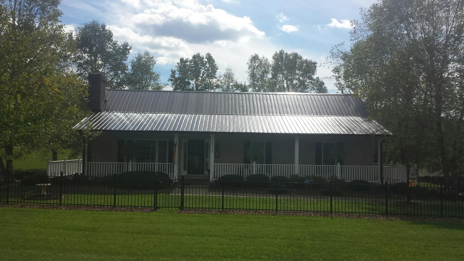 Gray metal roof on a brick ranch with a full width front porch — Gutter Guard Installation work by our crew in Richwood